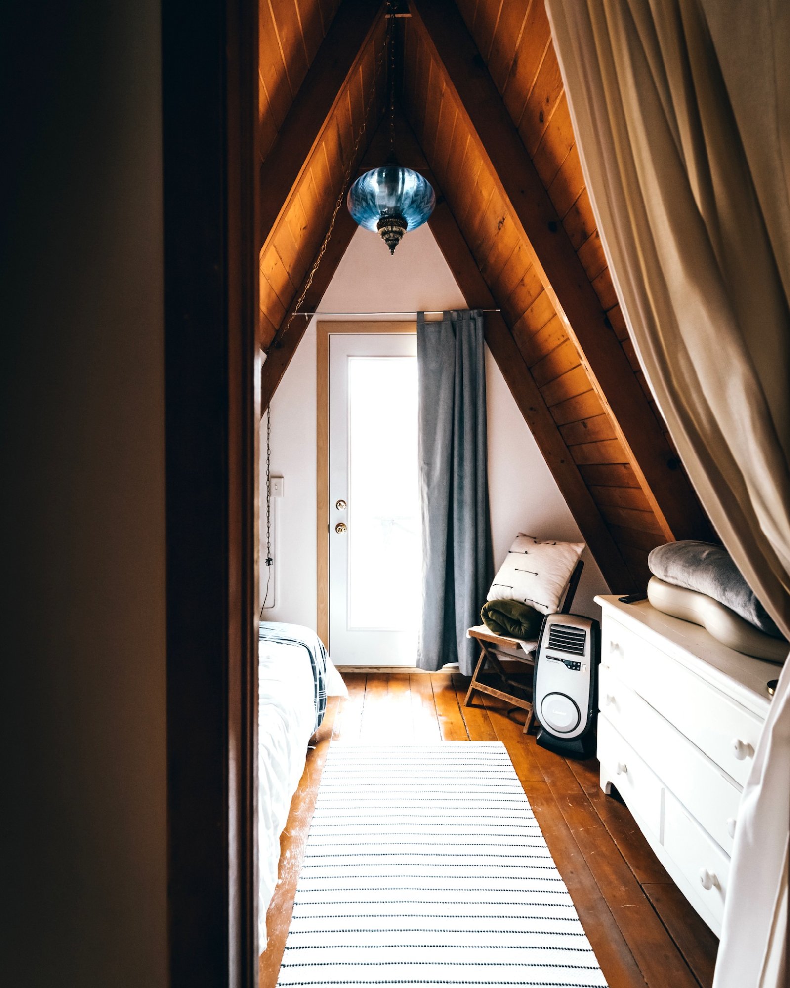 Interior loft of The Triangle showing exposed A-frame pine beams and warm wood tones